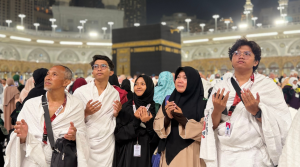 Jamaah umrah Adam Internasional sedang berdoa khusyuk di depan Ka'bah Masjidil Haram pada malam hari.